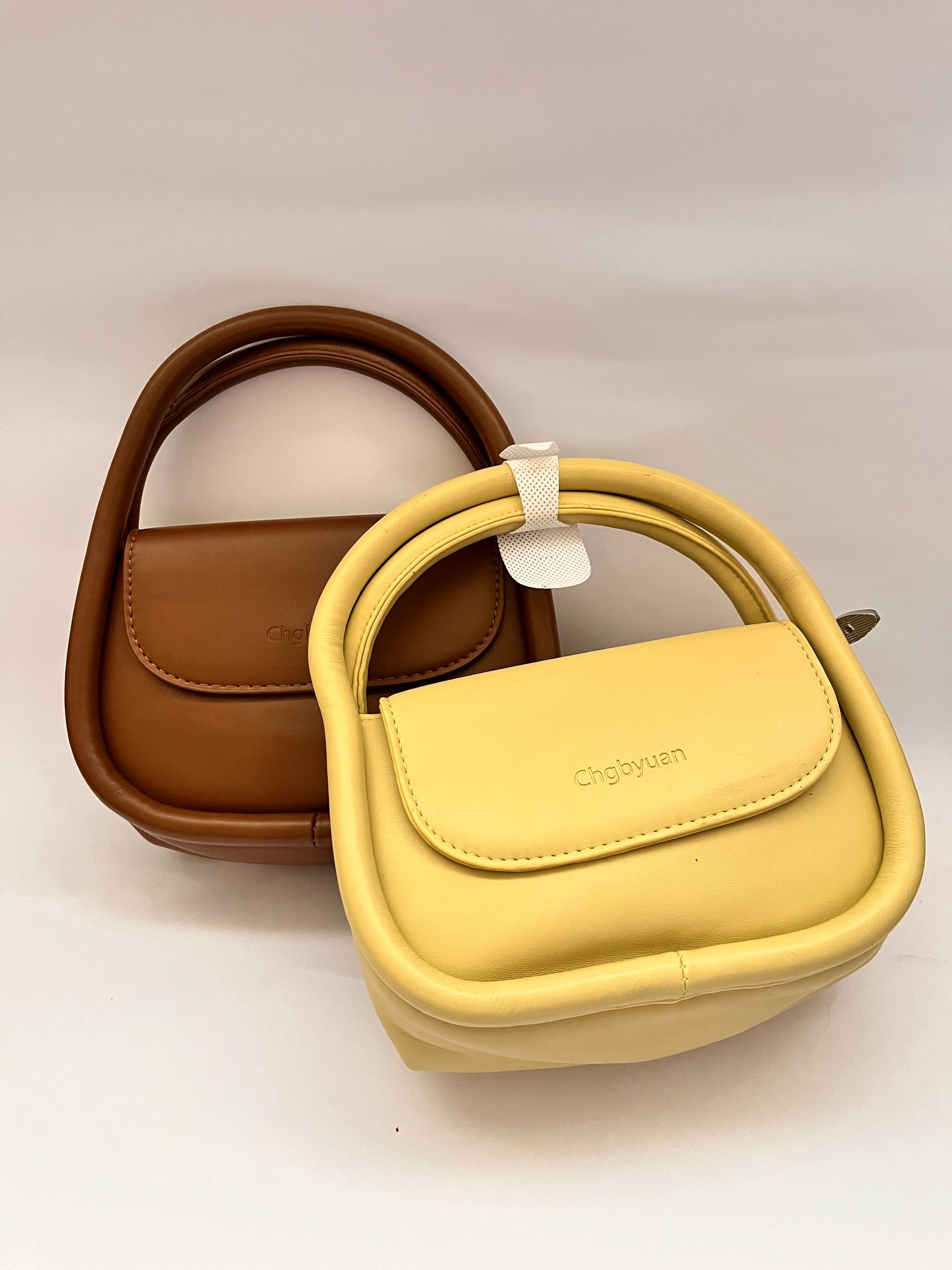 Elegant brown and yellow handbags displayed, showcasing modern leather fashion accessories.